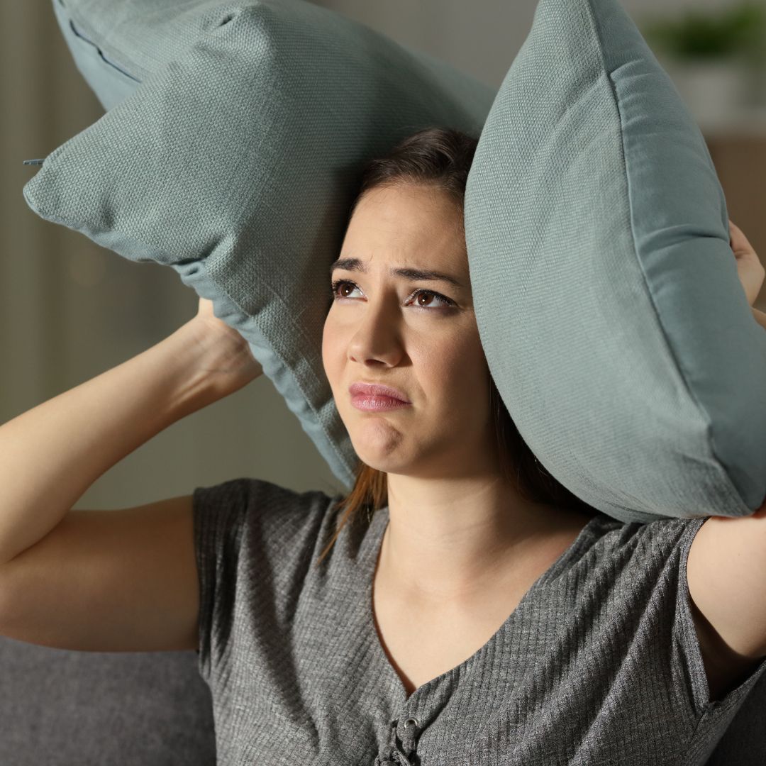 woman covering ears with a pillow