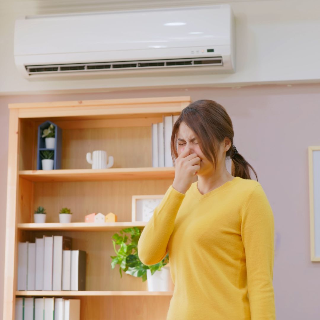 woman holding her nose near air vent
